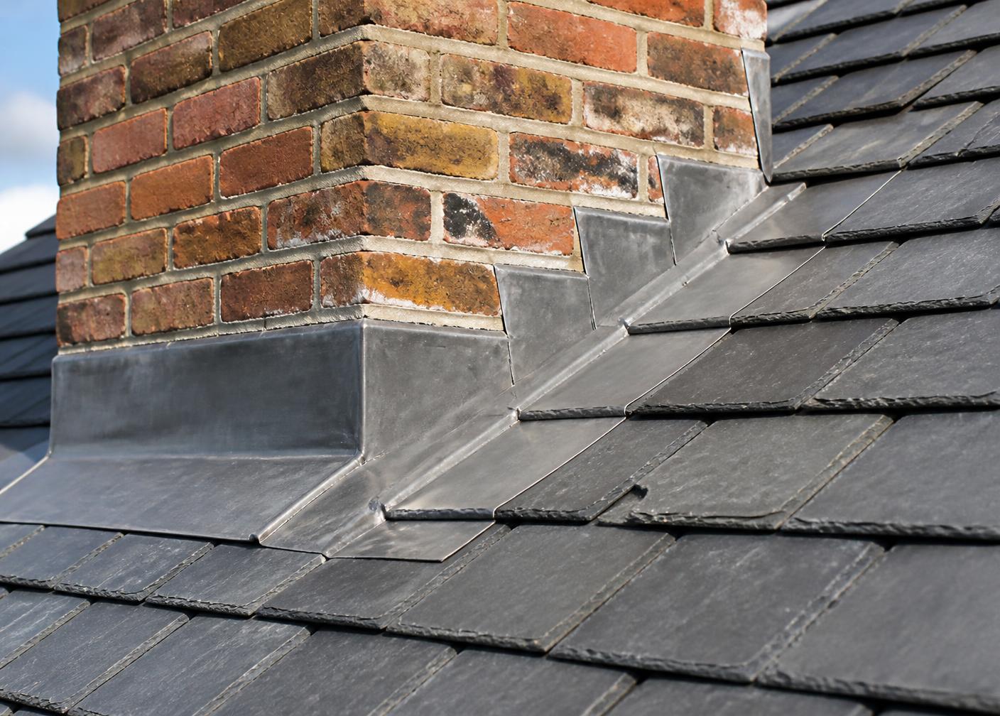 New lead flashing stepped into a slate roof around a brick chimney